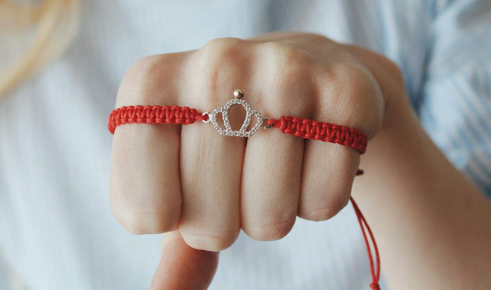 closeup-shot-red-thread-bracelet-with-silver-crown-pendant-female-s-hand_181624-44853.webp copy